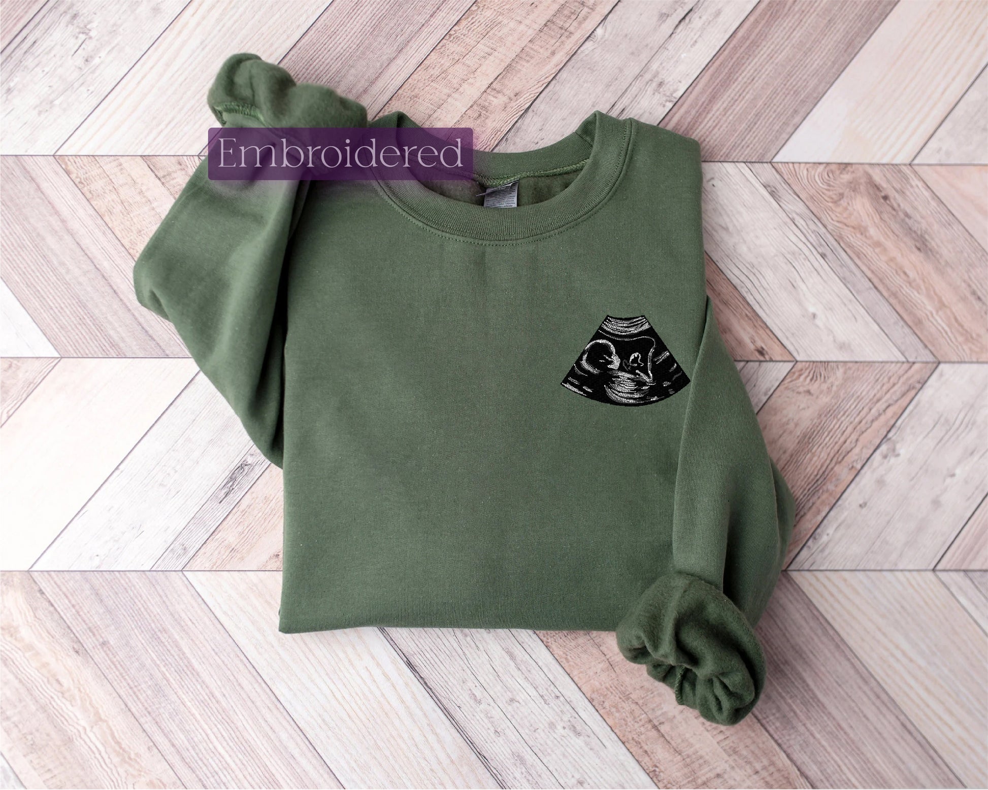 a green sweatshirt with a black cat embroidered on it