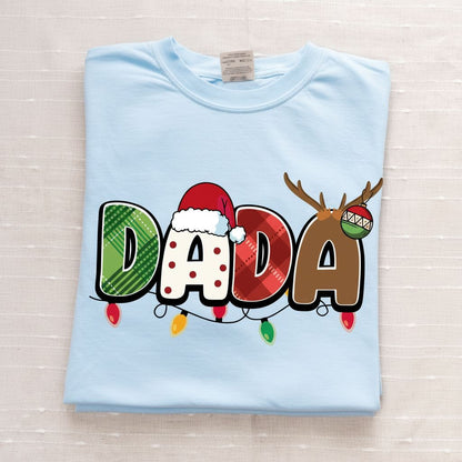 A light blue t-shirt with the word "DADA" printed on it, along with various holiday-themed elements such as a Santa hat, reindeer antlers, and Christmas lights.