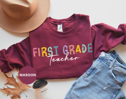 a maroon shirt that says first grade teacher next to a pair of jeans and a