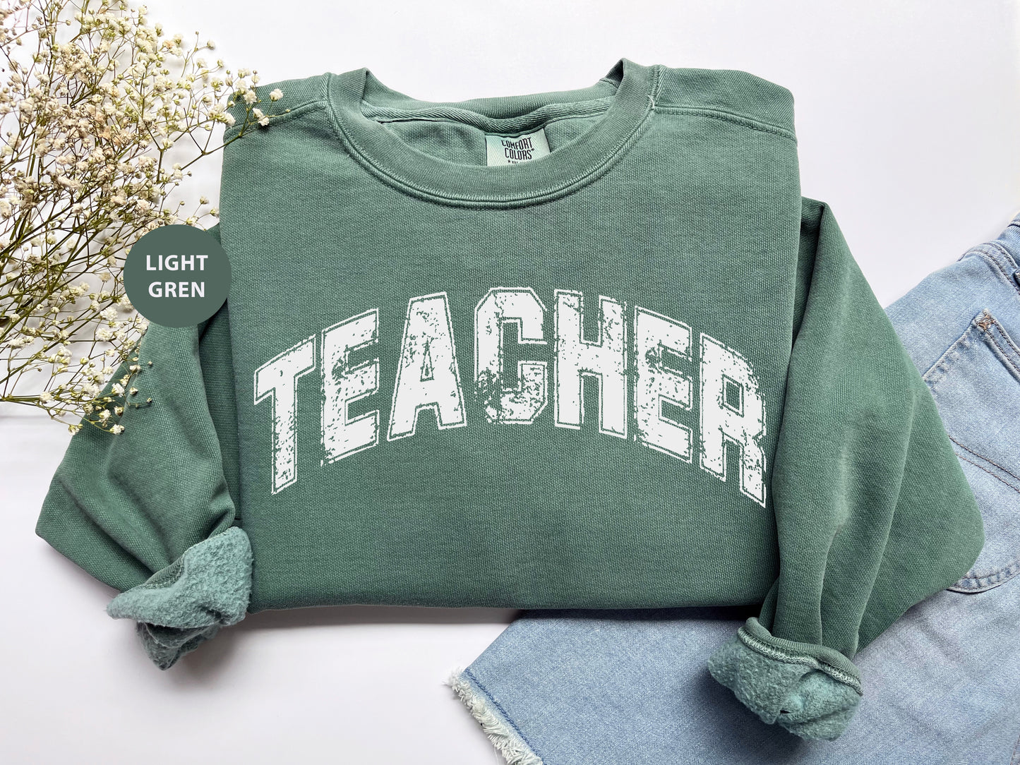 a green sweatshirt with the word teacher printed on it