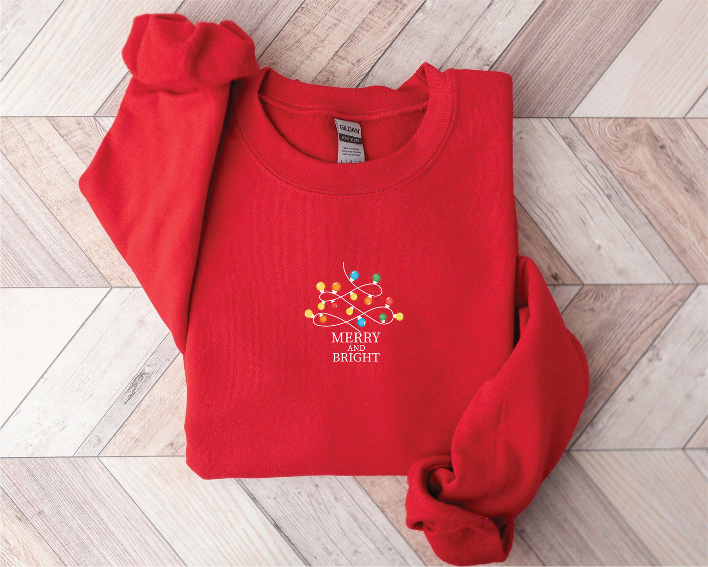 A red sweater with a white text logo on it, placed on a wooden surface.
