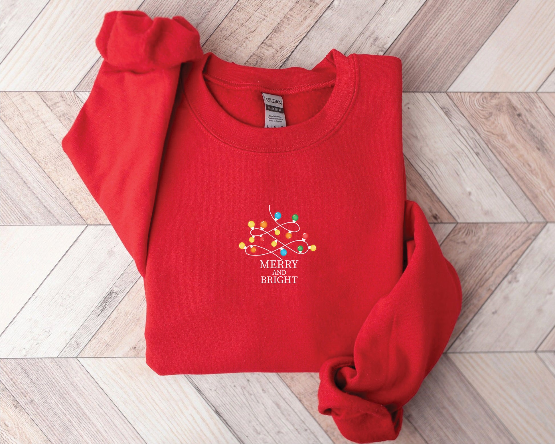 A red sweater with a white text logo on it, placed on a wooden surface.