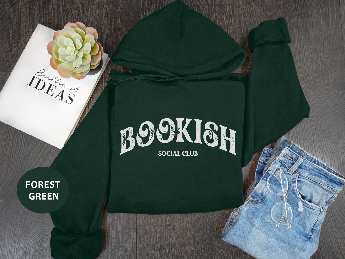 a green hoodie with the words bookish on it next to a pair of