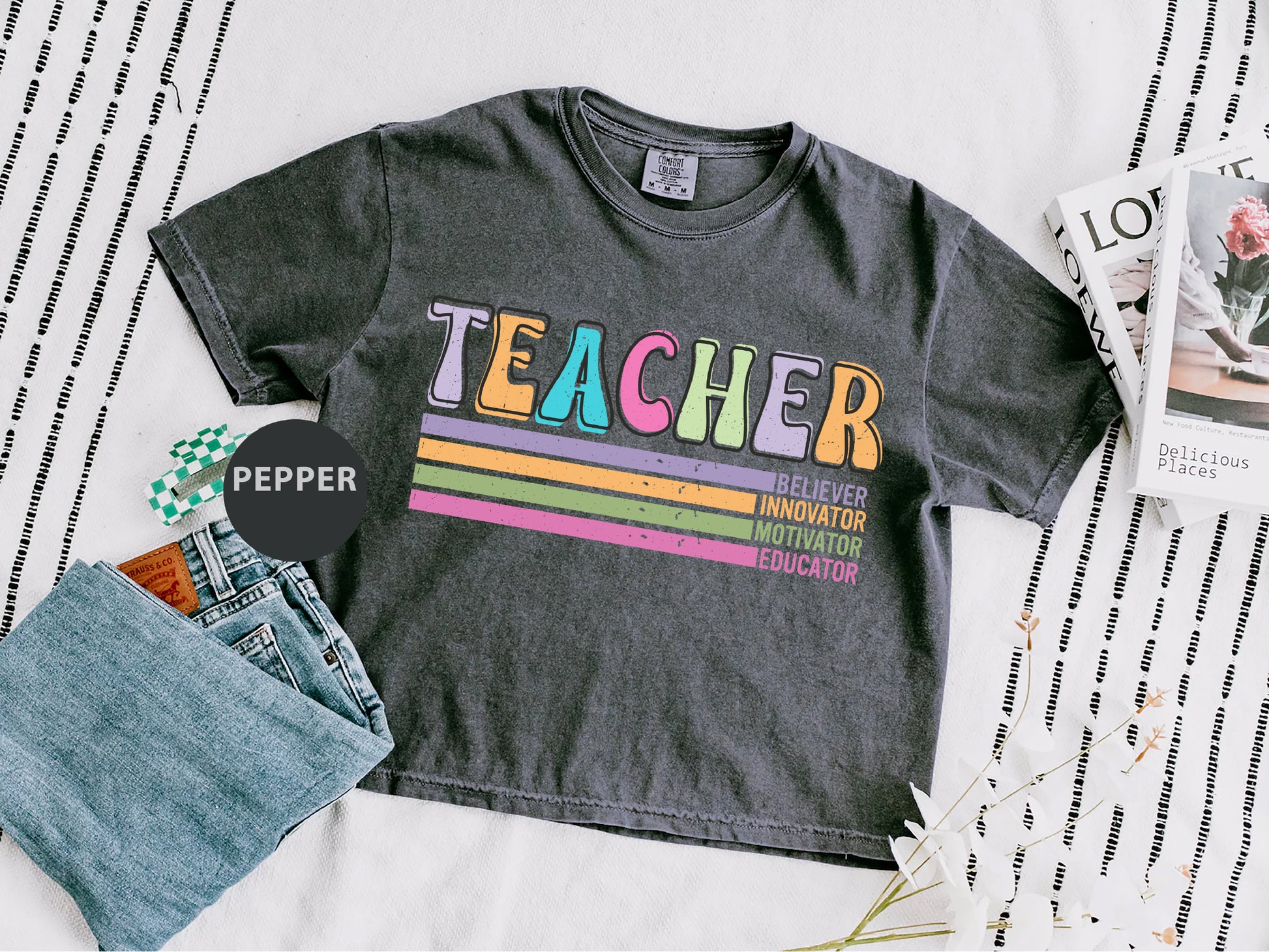 a t - shirt with the words teacher on it next to a pair of jeans