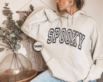 a woman wearing a white hoodie with the words spooky on it