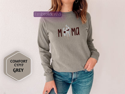 a woman wearing a gray shirt with the word mom printed on it