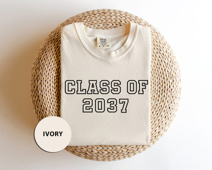 a t - shirt that says class of 2077 next to a wicker basket