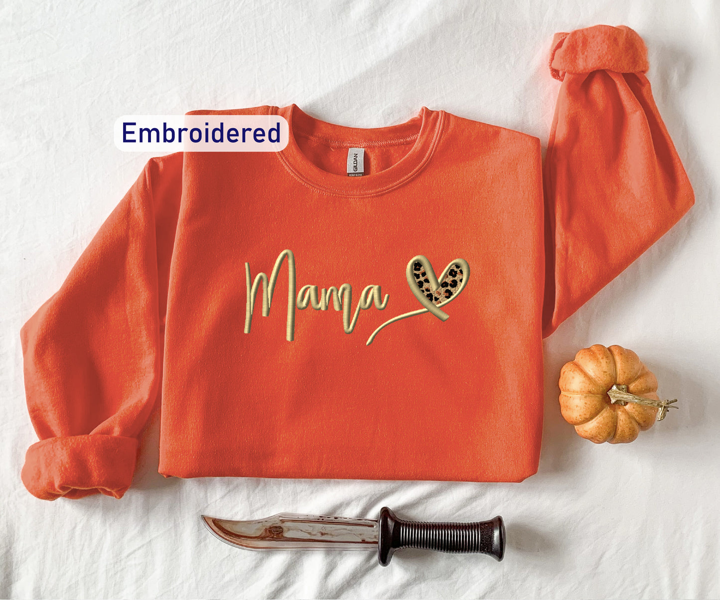 an orange shirt with the word mama written on it next to a knife and pumpkin