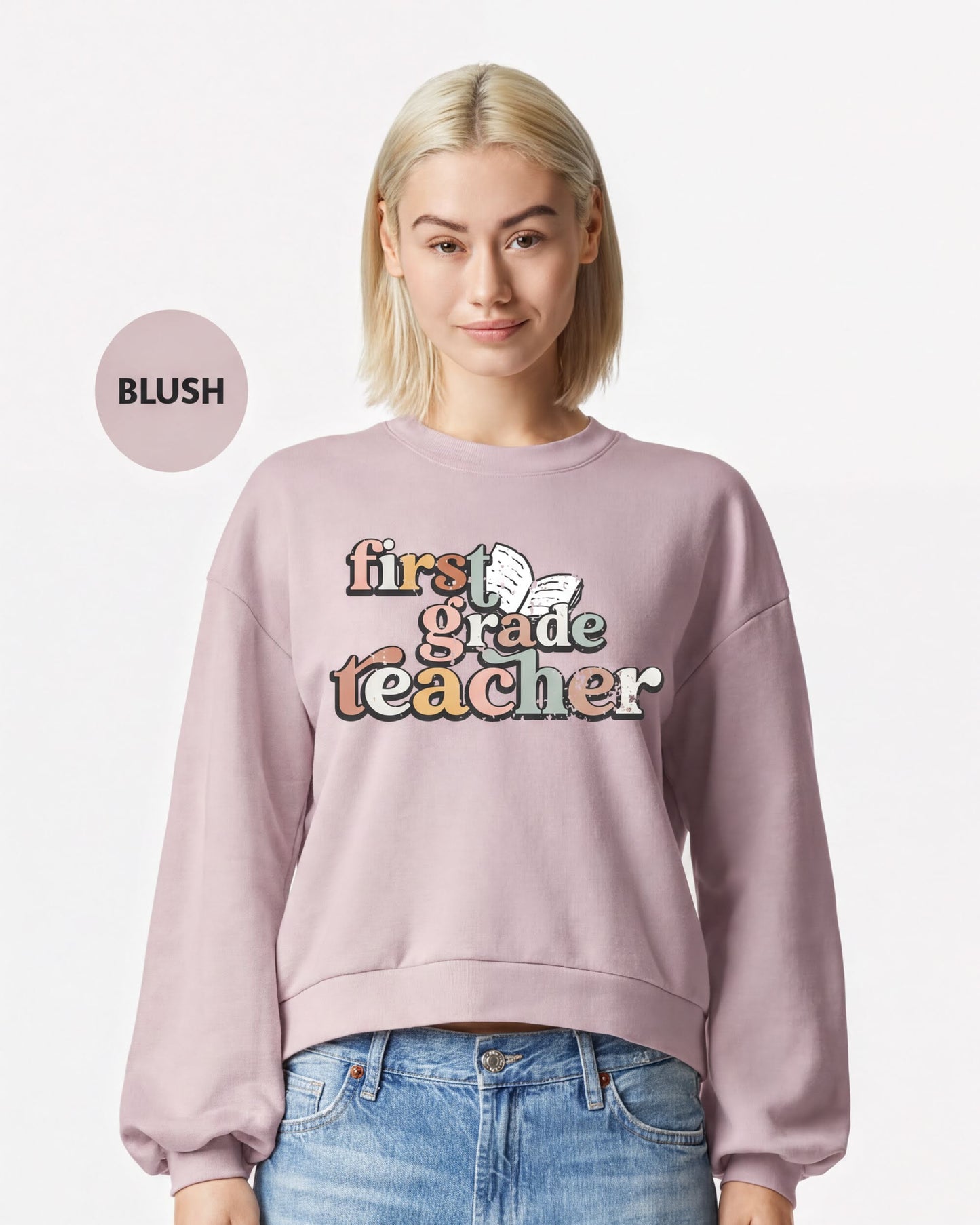 A woman wearing a pink sweatshirt with the text "first grade teacher" printed on it.