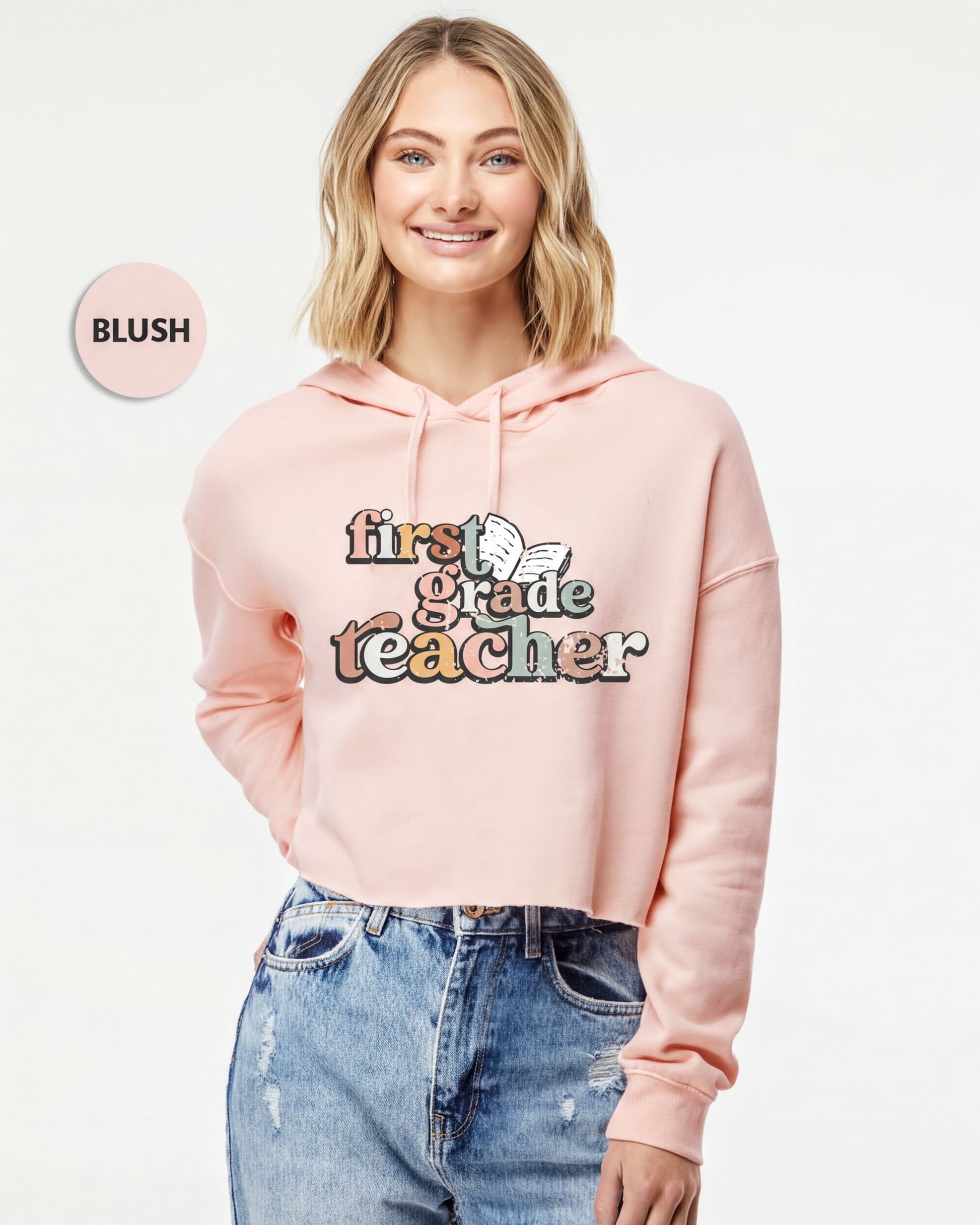 A smiling woman wearing a pink hoodie with the text "first grade teacher" printed on it.