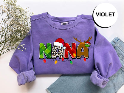 A purple sweatshirt with the word "NANA" printed on it, along with a Santa hat and Christmas lights, is displayed on a white background.