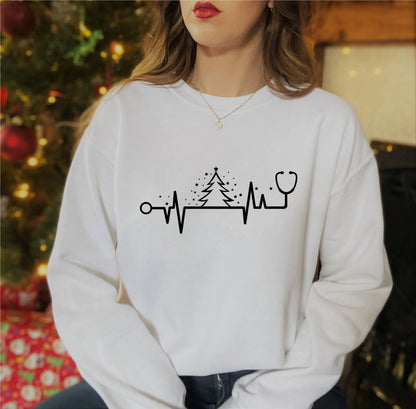 A woman wearing a white sweater with a graphic design of a stethoscope and a Christmas tree.
