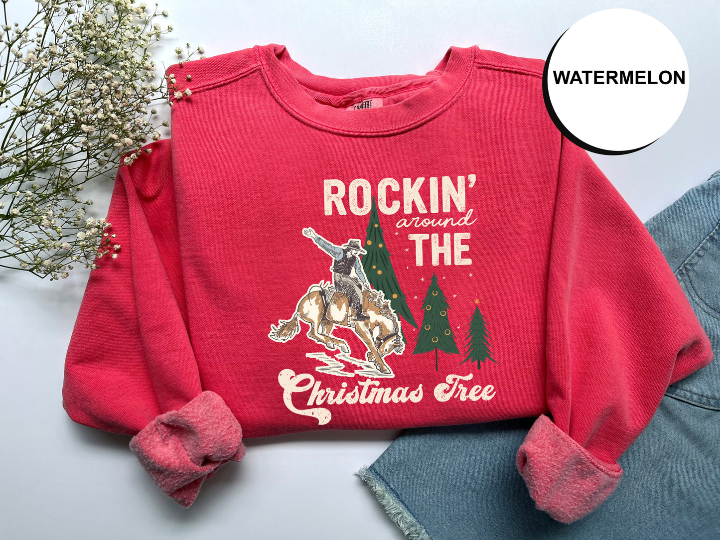 A red sweater with a graphic design and text printed on it, along with some flowers and a denim skirt.