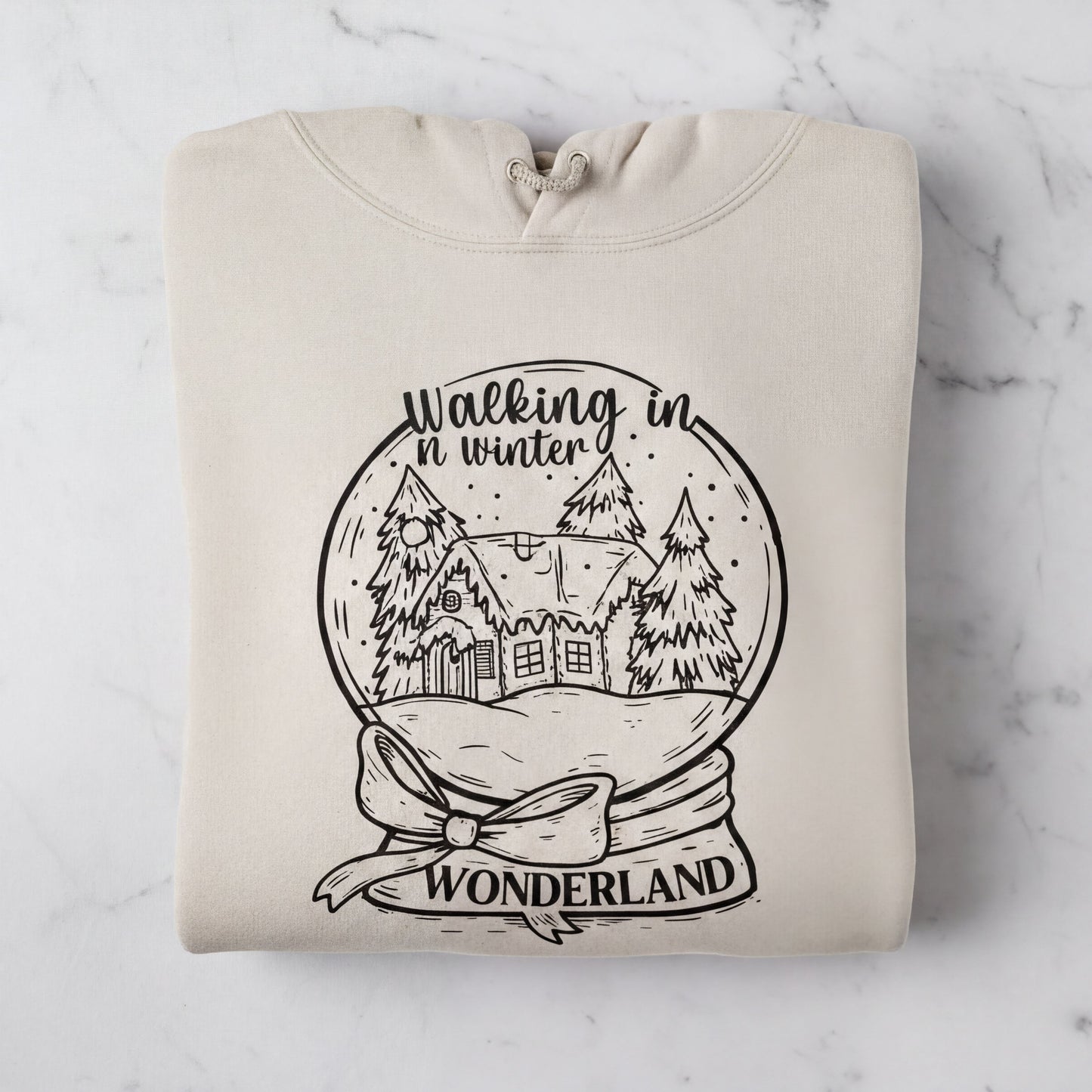 A beige hoodie with a black and white illustration of a snow globe depicting a winter scene, along with the text "Walking in winter wonderland" printed on it.