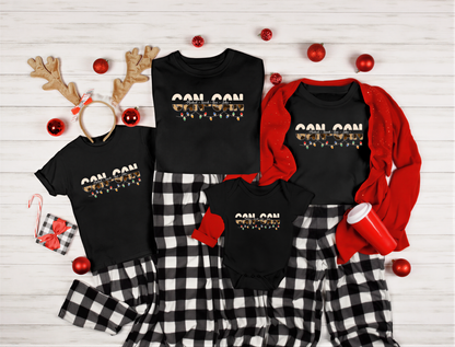 A collection of Christmas-themed clothing and accessories, including t-shirts, pajamas, and ornaments, arranged on a white wooden background.