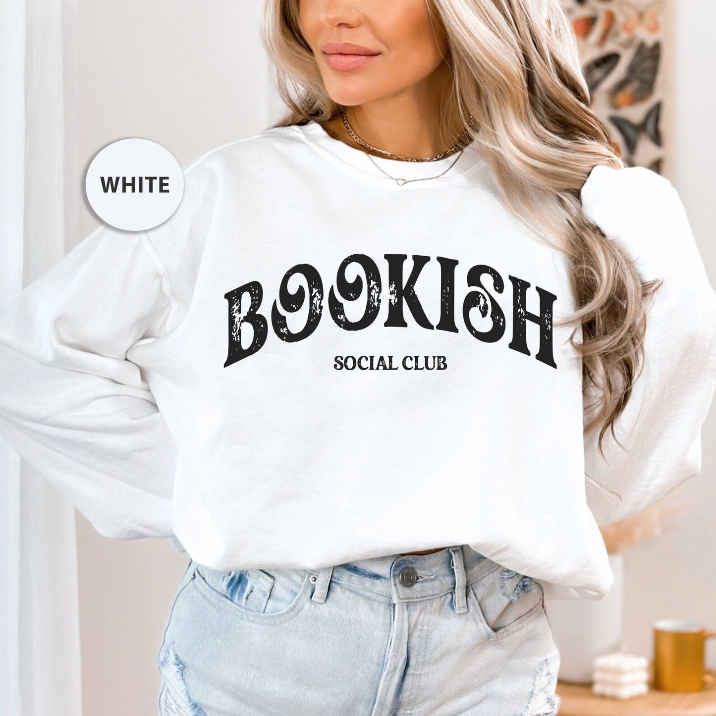 a woman wearing a white sweatshirt with a bookish social club on it