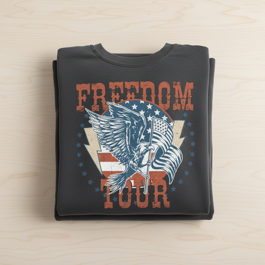 A black t-shirt with a graphic design featuring a large eagle holding a flag and the text "FREEDOM TOUR" printed on it.