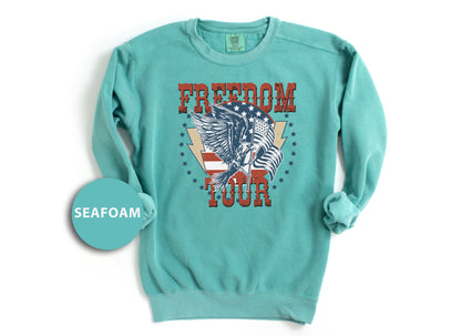 A turquoise long-sleeved shirt with a graphic design featuring an eagle and the text "FREEDOM TOUR" printed on it.