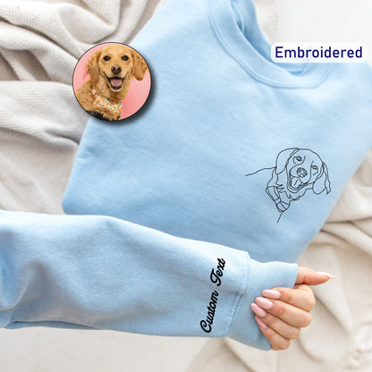 a person's hand holding a blue sweater with a picture of a dog on