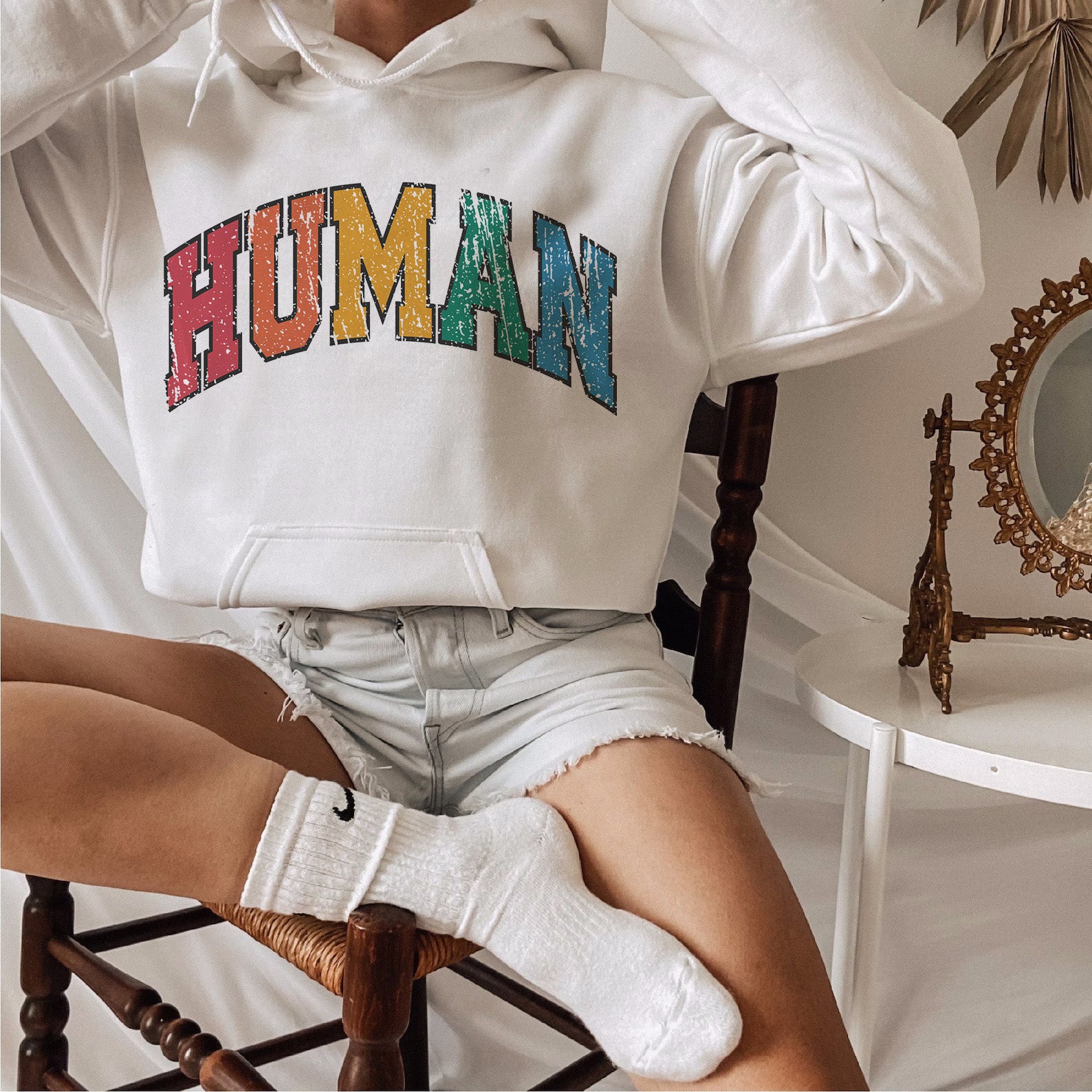 a woman sitting in a chair wearing a white hoodie