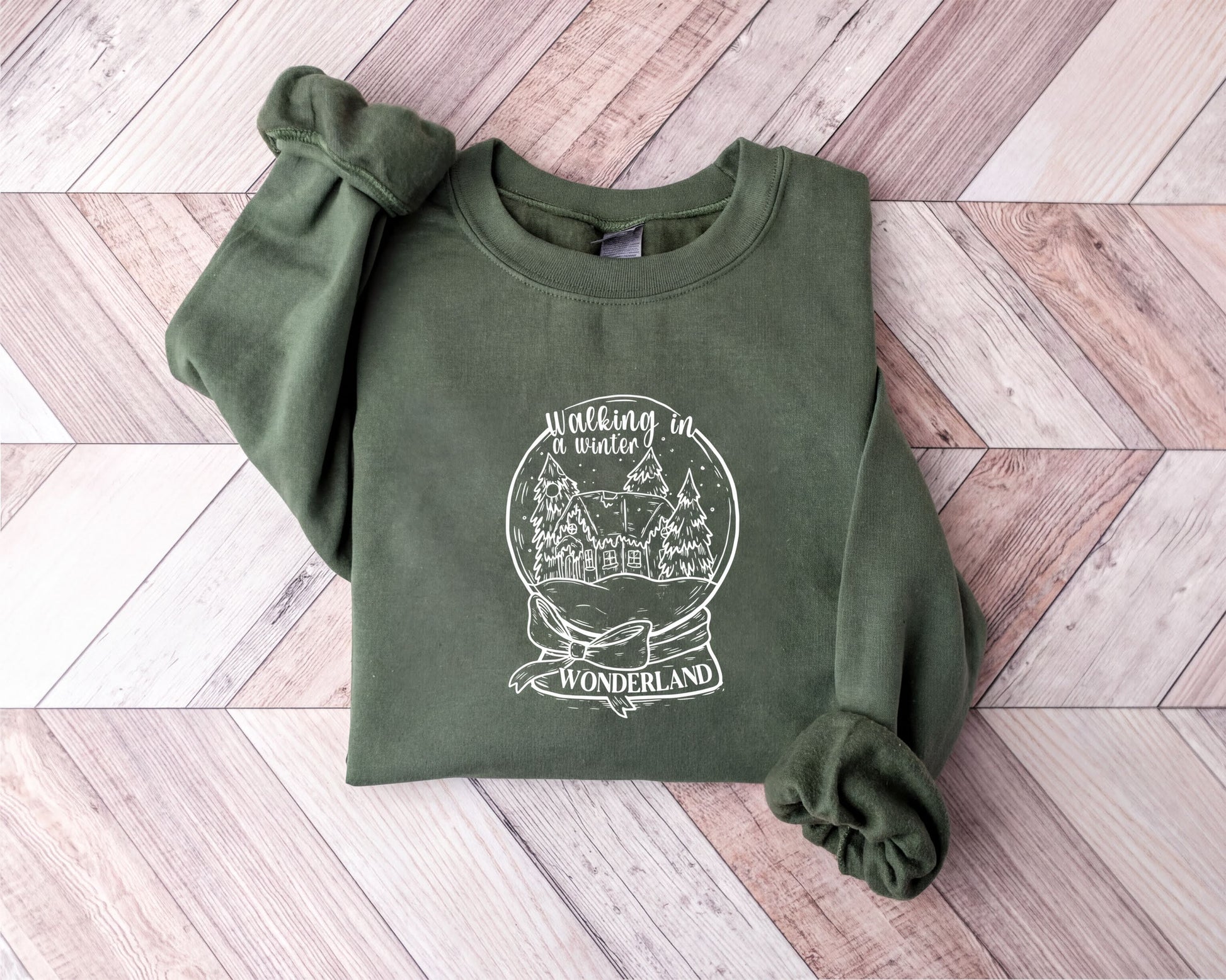 A green sweatshirt with a white graphic design on it, laid out on a wooden surface.