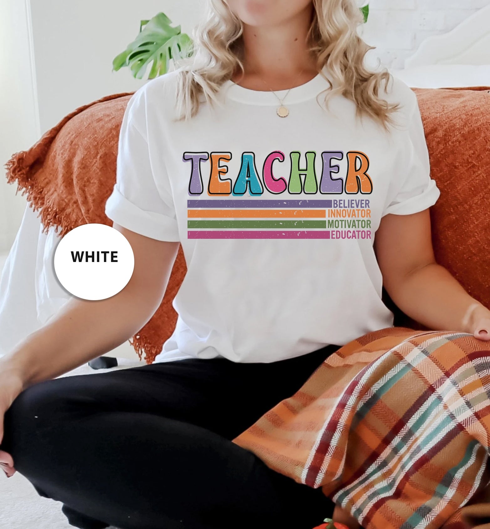 a woman sitting on a couch wearing a teacher shirt