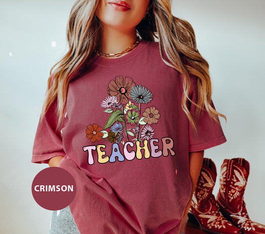 a girl wearing a teacher t - shirt with flowers on it