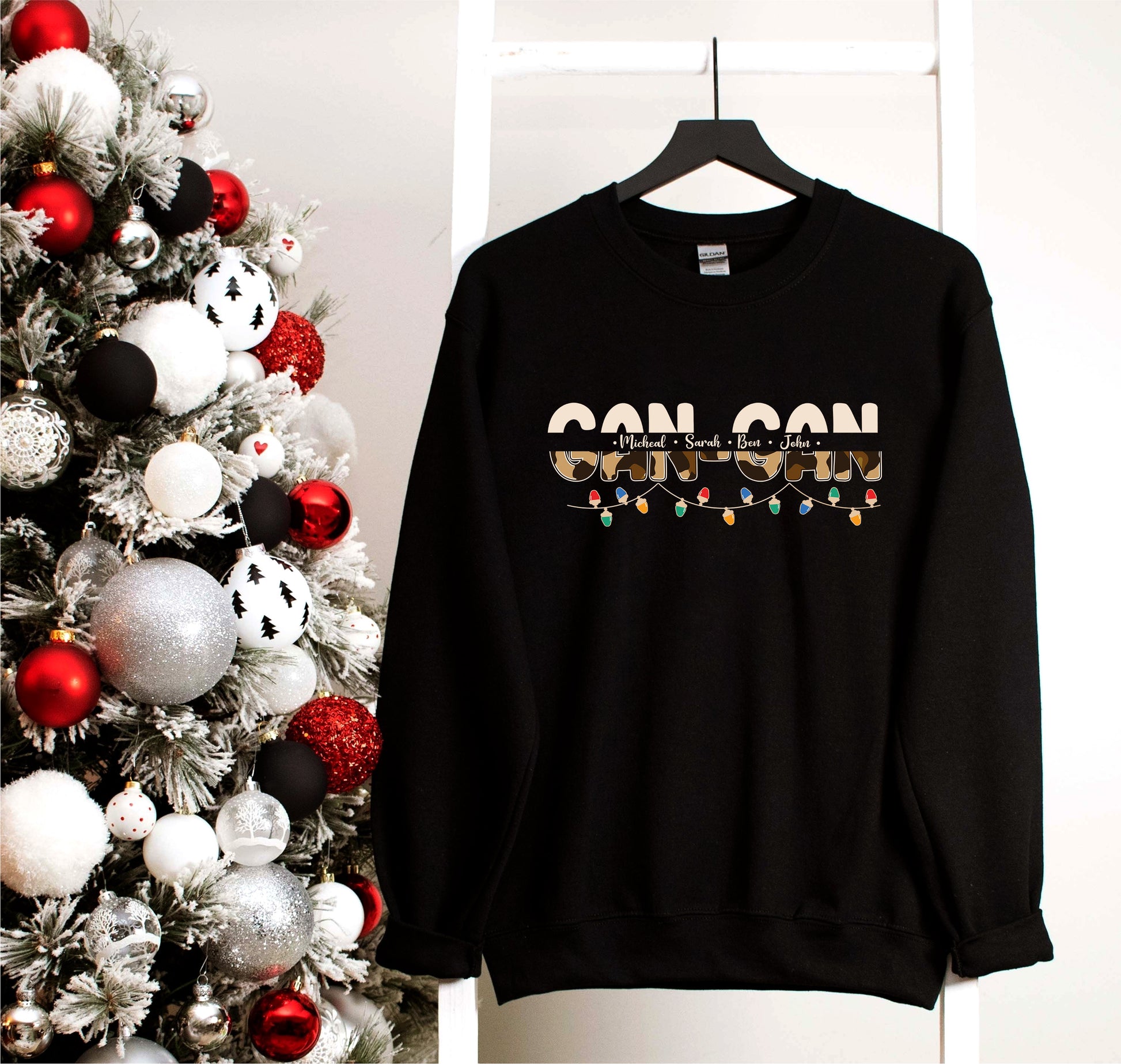 A black sweatshirt with the text "CONSON" printed on it, hanging on a white hanger next to a Christmas tree decorated with red and silver ornaments.