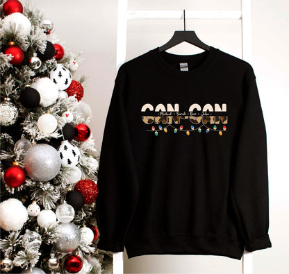 A black sweatshirt with the text "CONSON" printed on it, hanging on a white hanger next to a Christmas tree decorated with red and silver ornaments.