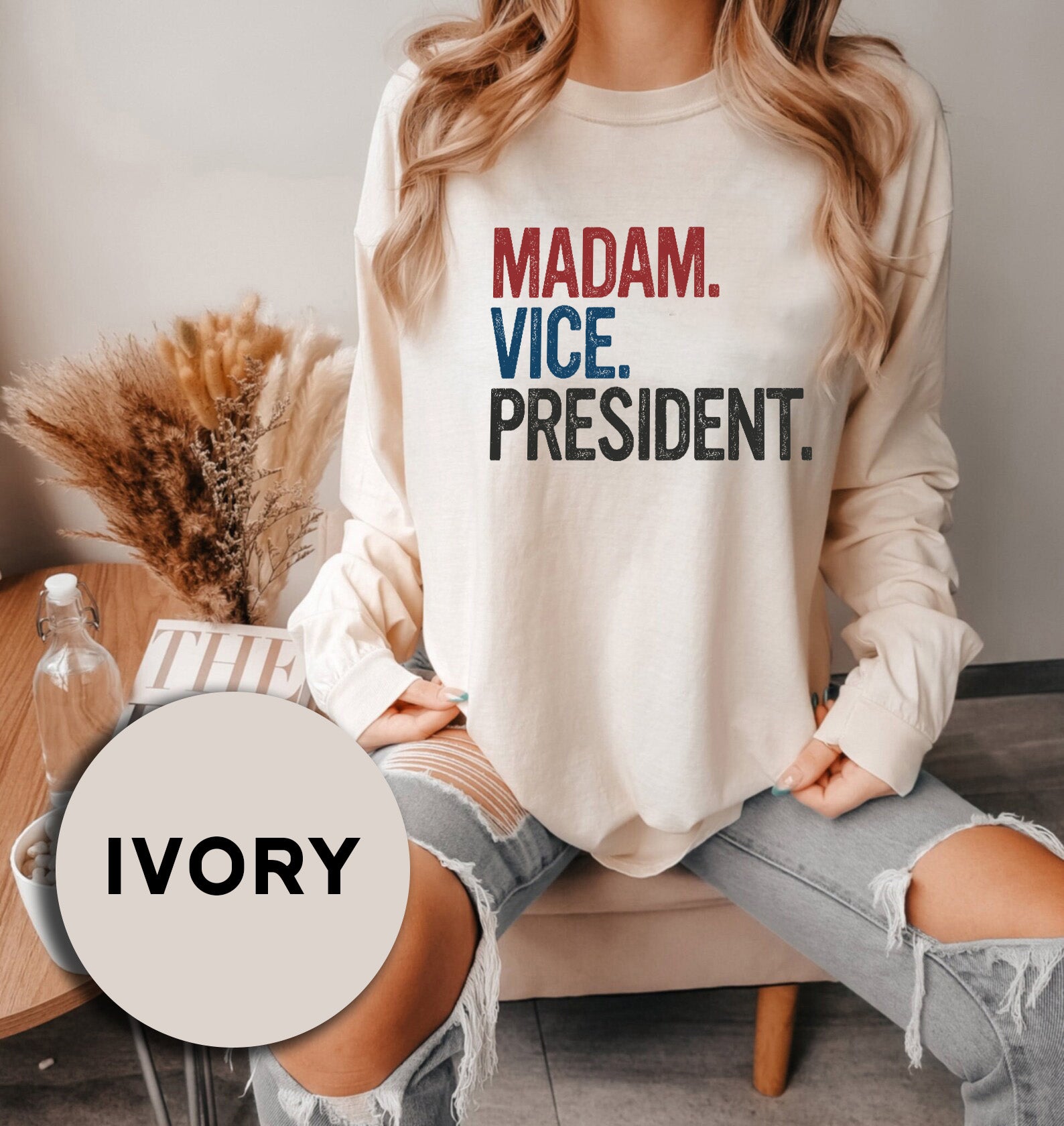 a woman sitting on a couch wearing a sweatshirt that says madam vice president