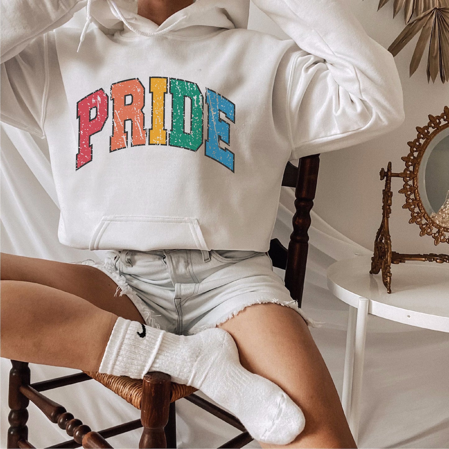 a woman sitting in a chair wearing a pride hoodie