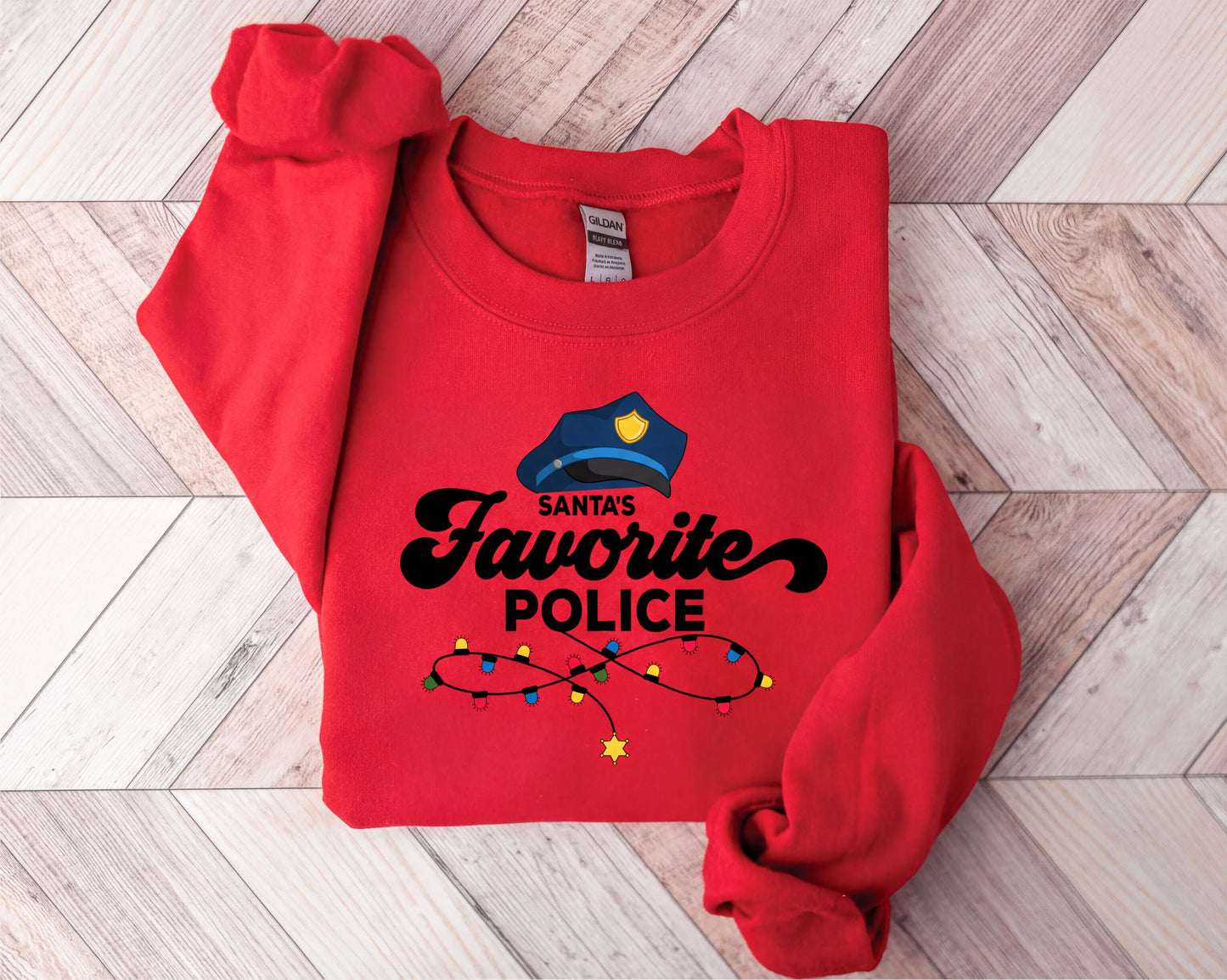 A red sweater with a graphic design on it, featuring a police officer's hat and the text "Santa's Favorite Police".