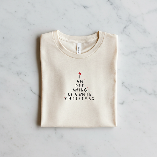 A white t-shirt with a Christmas-themed design printed on it, laid out on a marble surface.