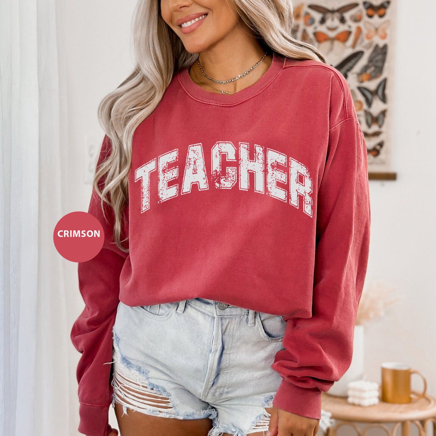 a woman wearing a red sweatshirt and denim shorts