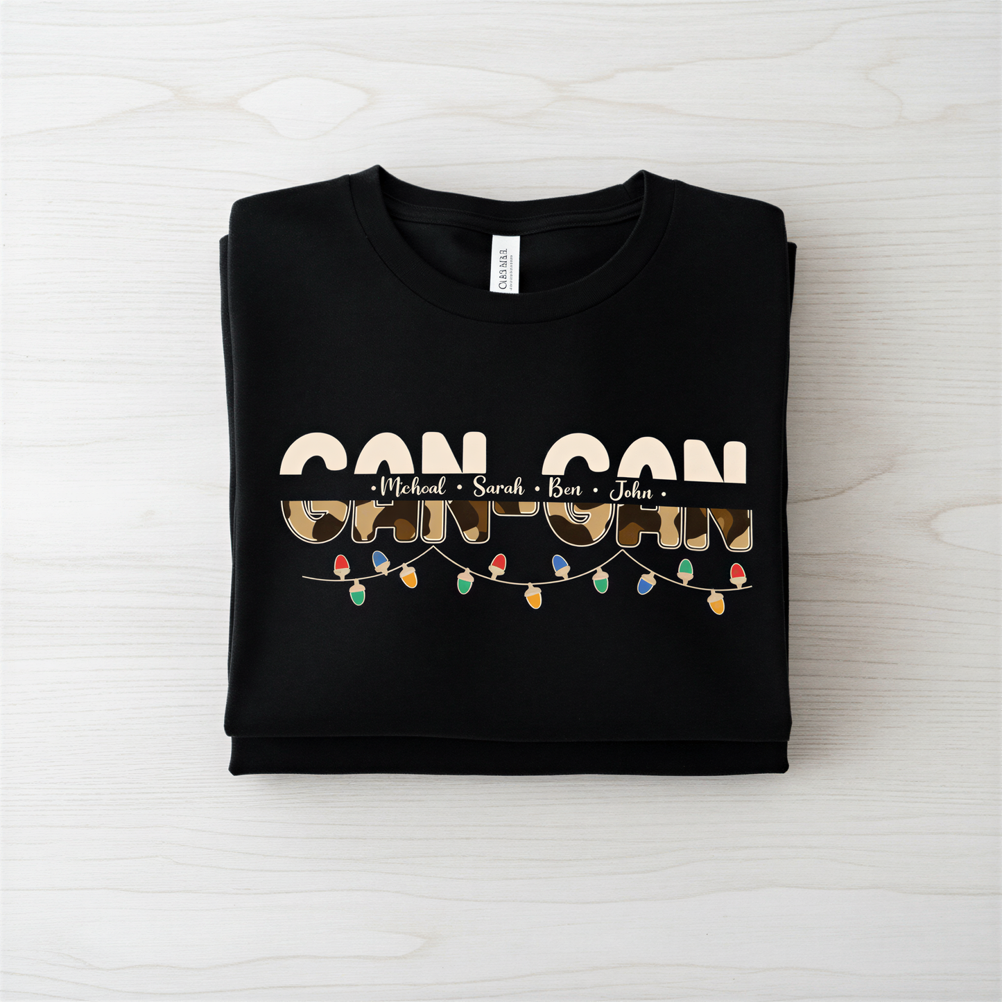 A black t-shirt with the text "CAN CAN" printed on it, along with the names "Michael", "Sara", and "Ben" written below it.