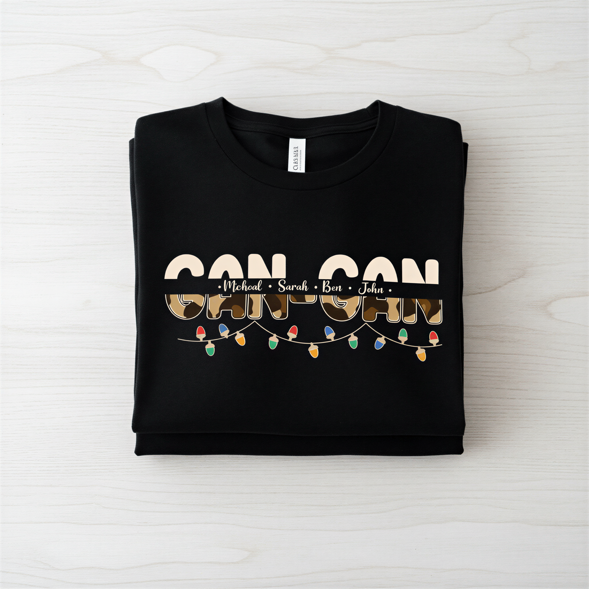A black t-shirt with the text "CAN CAN" printed on it, along with the names "Michael", "Sara", and "Ben" written below it.