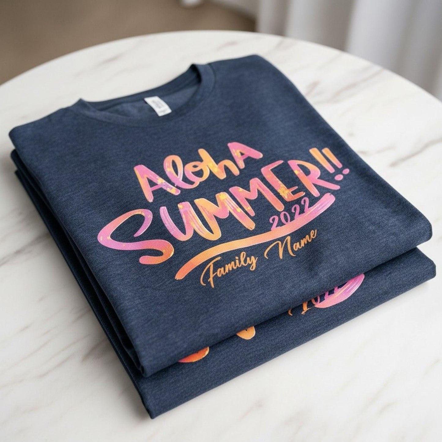 A dark blue t-shirt with the text "Aloha Summer! Family Name" printed on it, along with a colorful design.