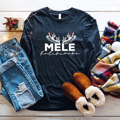 A casual outfit consisting of a black long-sleeved shirt with a white graphic design, distressed blue jeans, brown boots, and a colorful plaid scarf is laid out on a wooden surface.