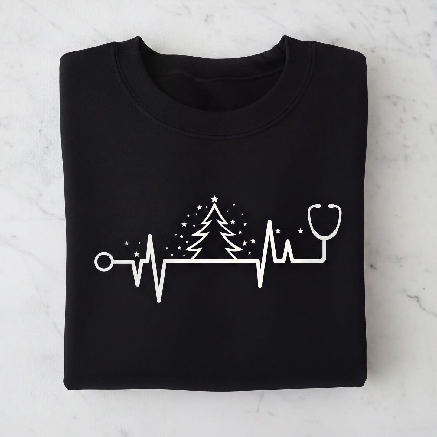 A black t-shirt with a white graphic design depicting a stethoscope, a Christmas tree, and a heart rate monitor line.