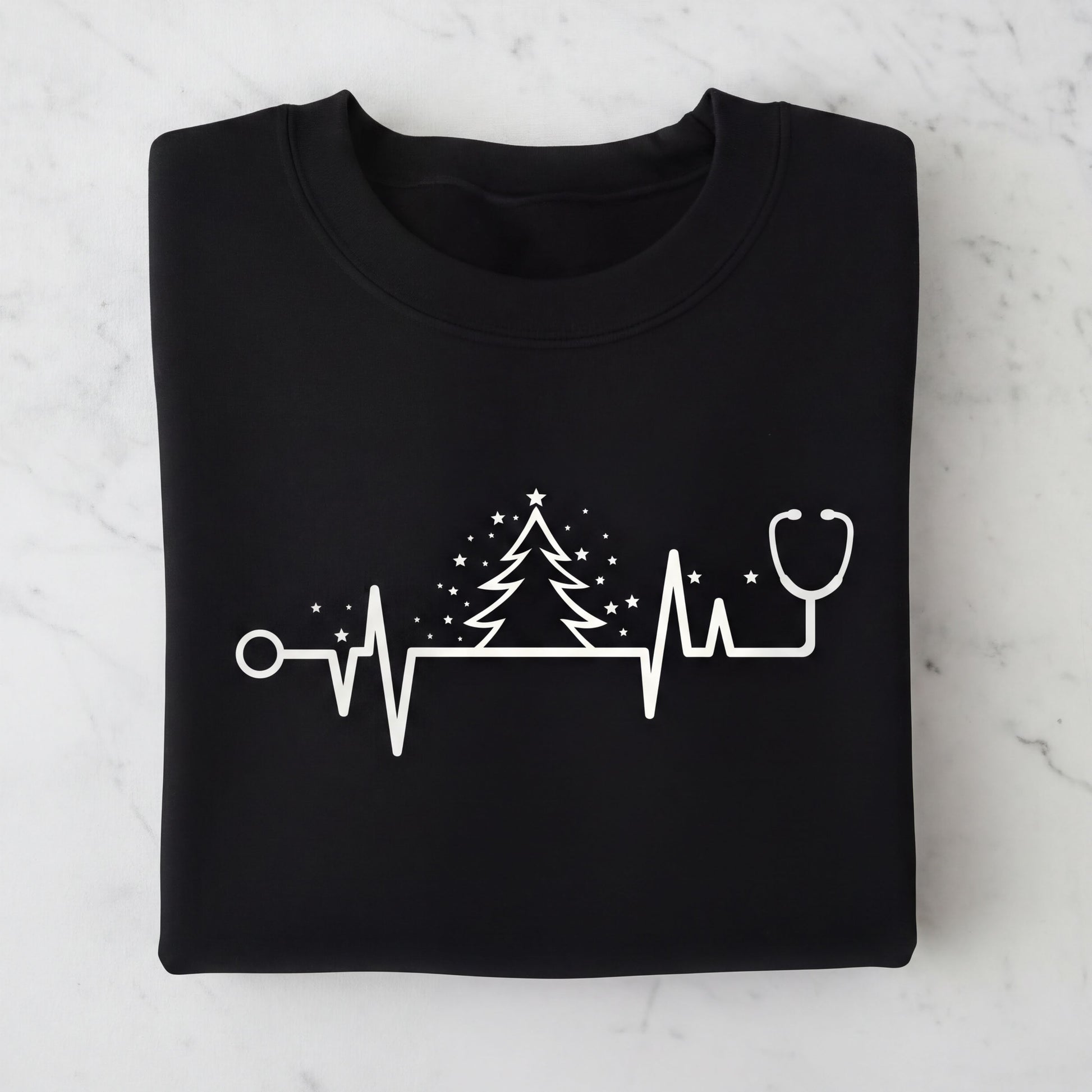 A black t-shirt with a white graphic design depicting a stethoscope, a Christmas tree, and a heart rate monitor line.