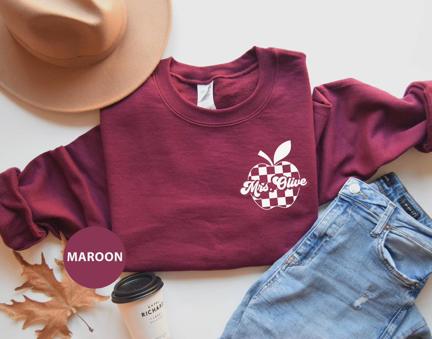 a maroon shirt with an apple on it next to a hat and a pair of