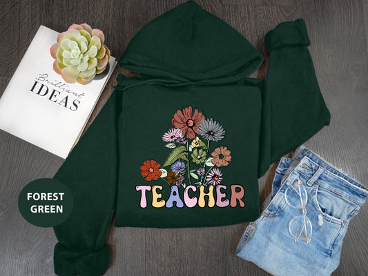 a green hoodie with flowers and the words teacher on it