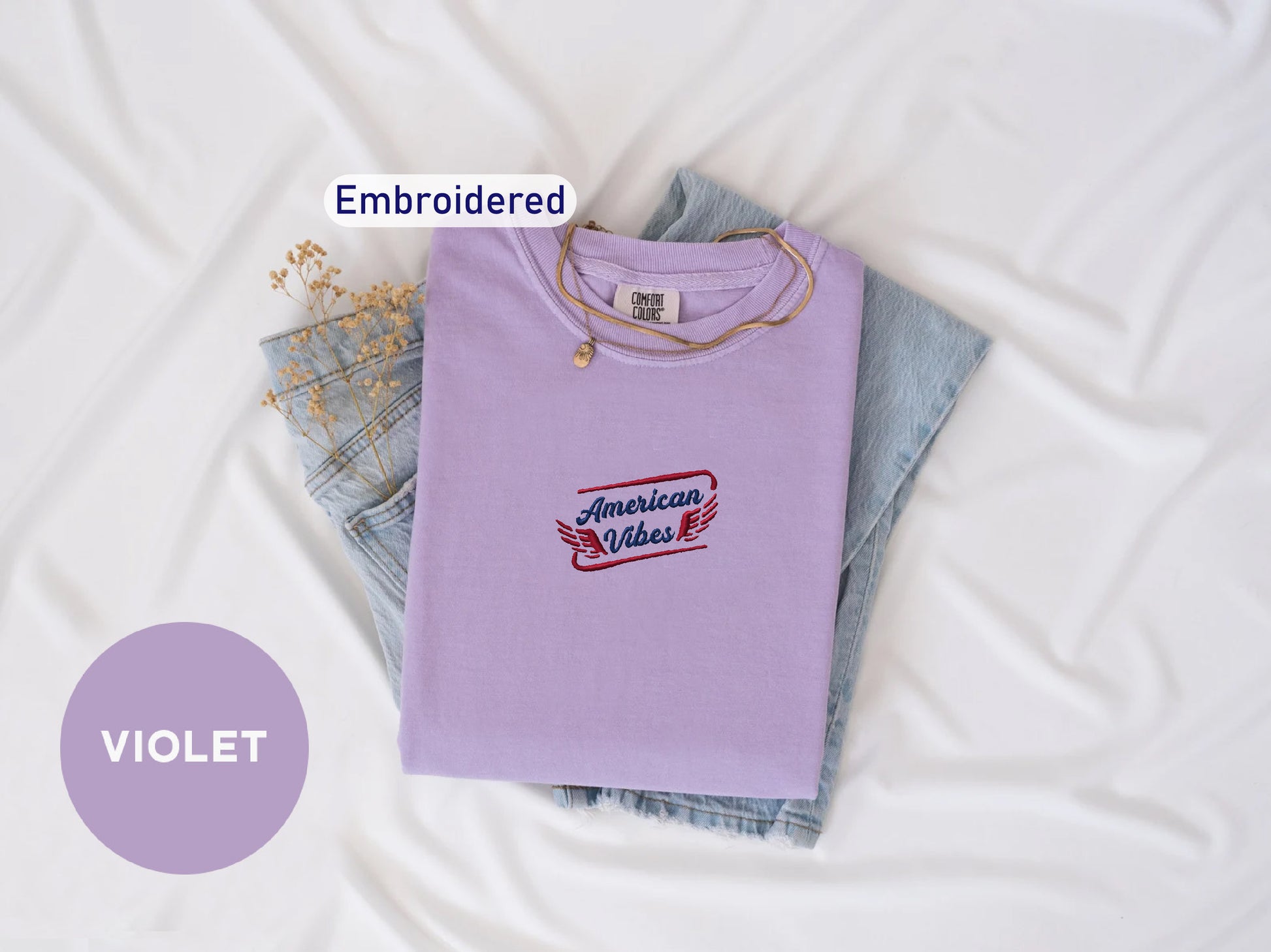 a purple t-shirt with a red and blue embroidered design, a pair of blue jeans, and a necklace. The text "Embroidered" is displayed above the t-shirt, and the word "VIOLET" is written below the jeans.