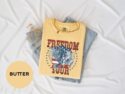 a yellow t-shirt with a graphic design, a pair of blue jeans, and some dried flowers on a white background.