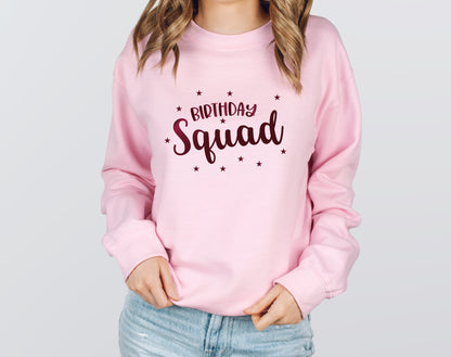 A woman wearing a pink sweatshirt with the text "Birthday Squad" printed on it.