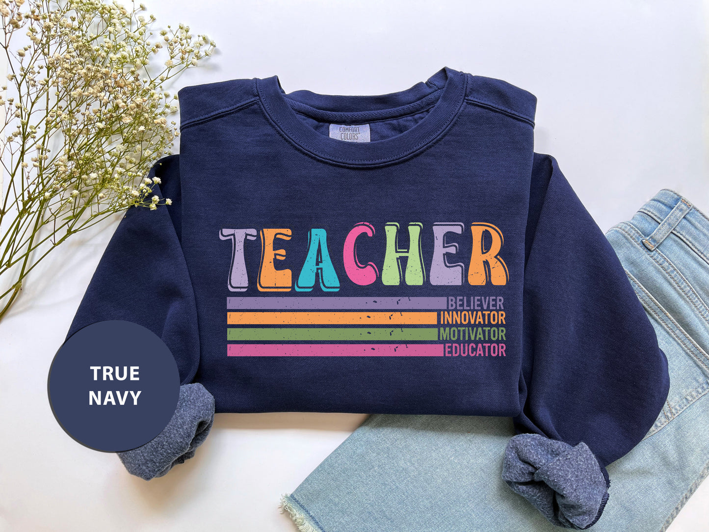 a t - shirt that says teacher on it next to a pair of jeans