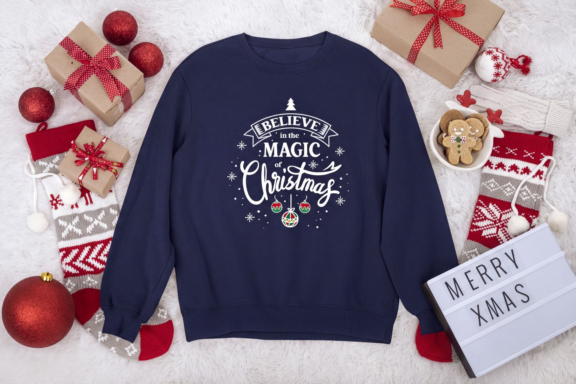 A navy blue sweatshirt with a Christmas-themed design, surrounded by various holiday decorations and gifts, including a sign that says "Merry Xmas".