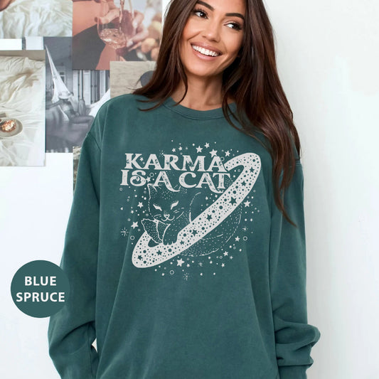 a woman wearing a green sweatshirt that says karma is a cat