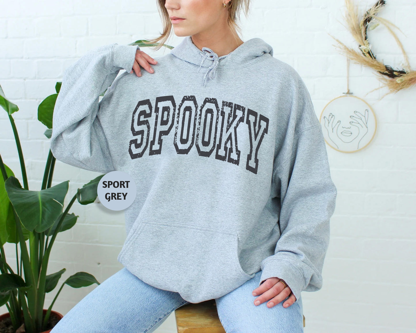 a woman sitting on a stool wearing a hoodie