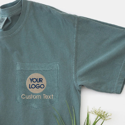 a green t - shirt with a logo on it next to a plant